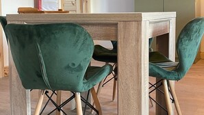 Una mesa de comedor con cuatro sillas tapizadas en verde.