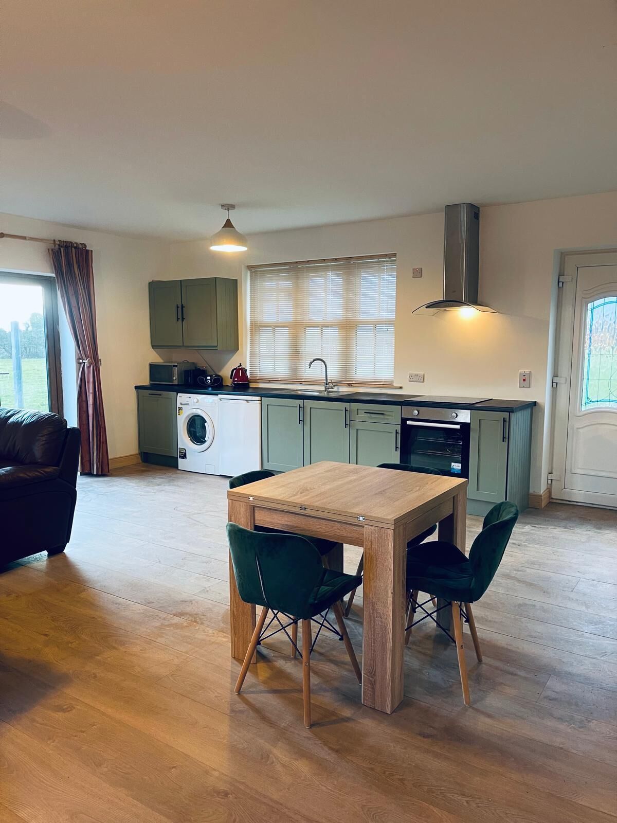 A compact kitchen with a dining table and chairs, a washing machine, and a microwave.