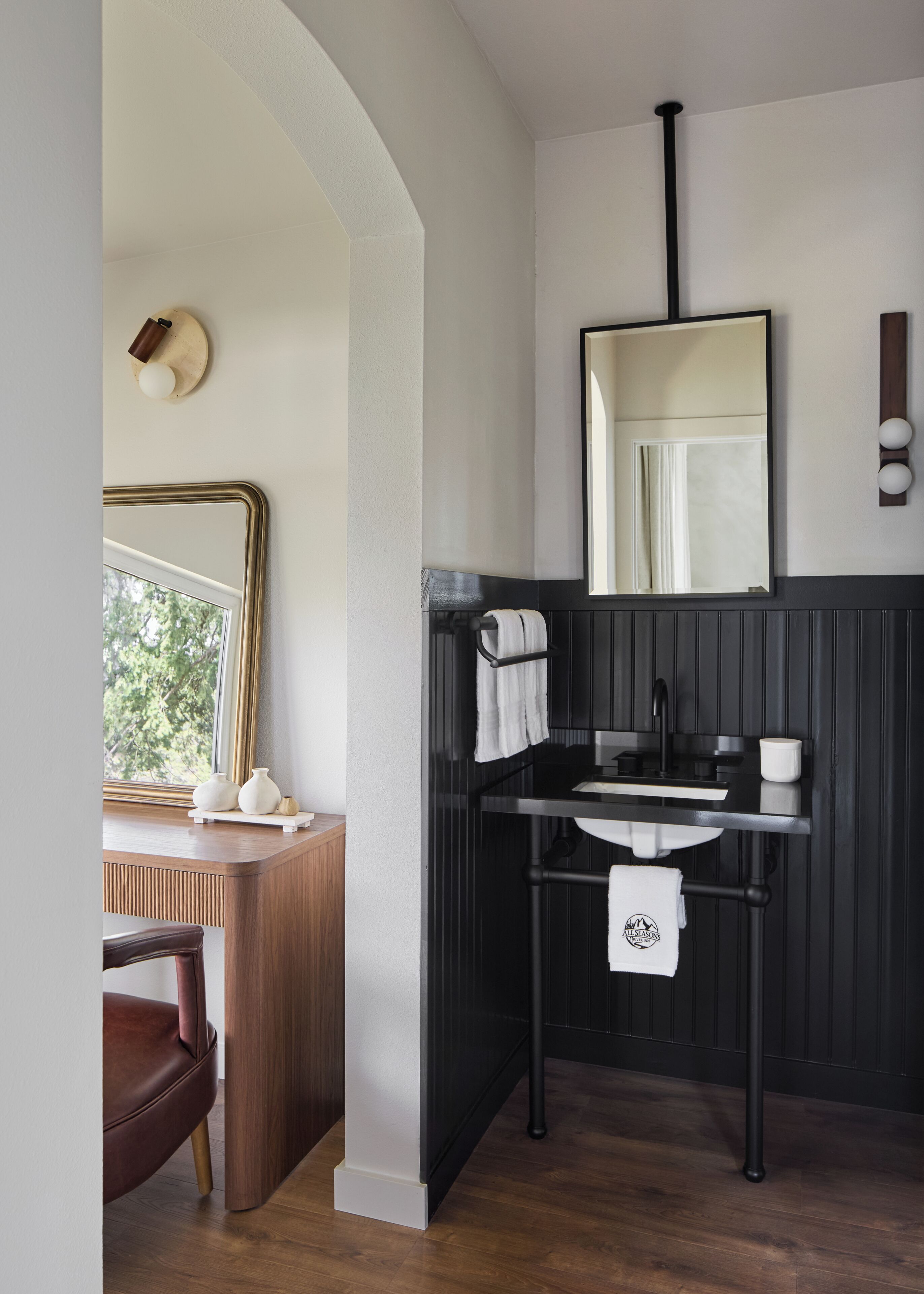 A bathroom with a wooden vanity, a black sink, a mirror, and a towel rack.