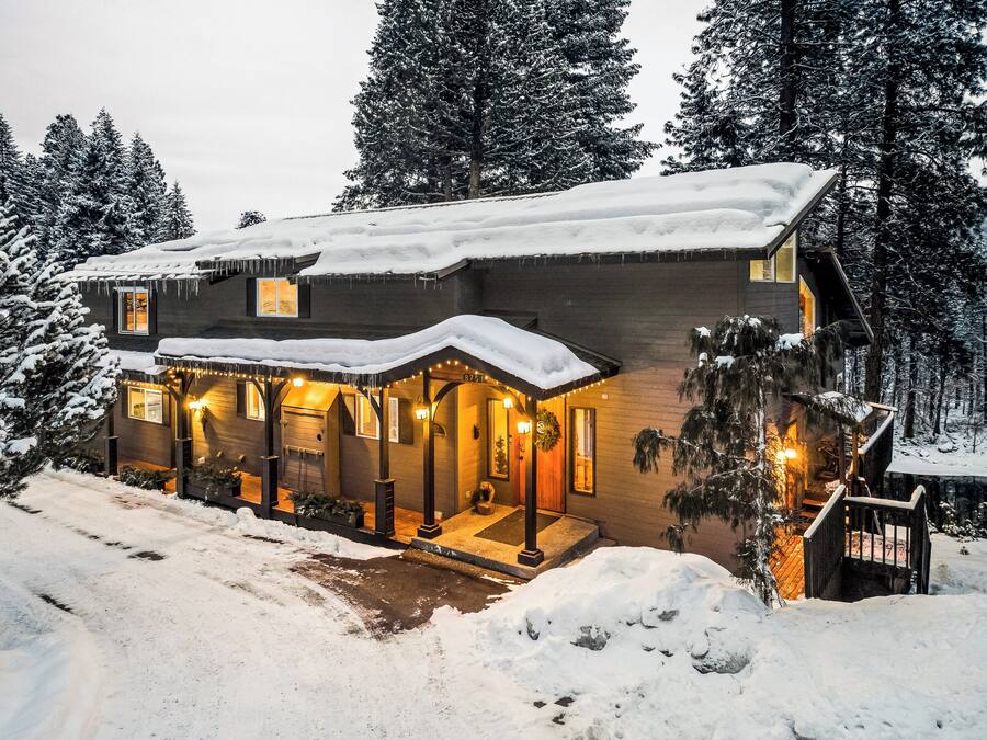 A two-story lodge with a snow-covered roof and a warm, inviting entrance.