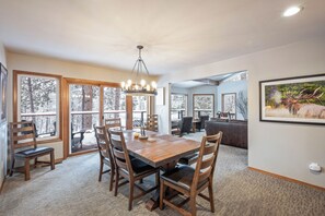 A dining area with a wooden table and chairs, large windows, and a chandelier. - All Seasons River Inn (Leavenworth)