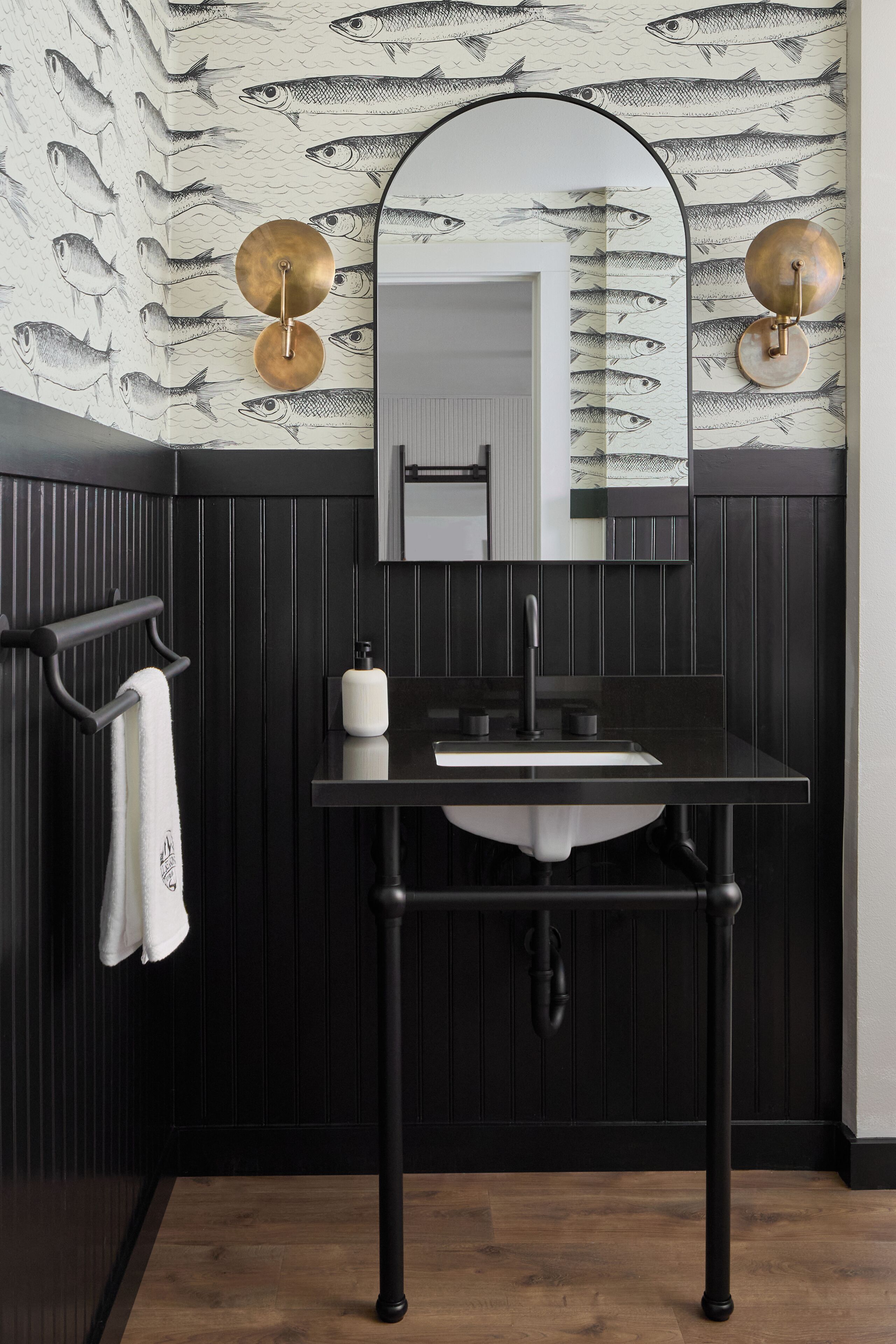 A modern bathroom with a black vanity, a white sink, and a mirror above it.