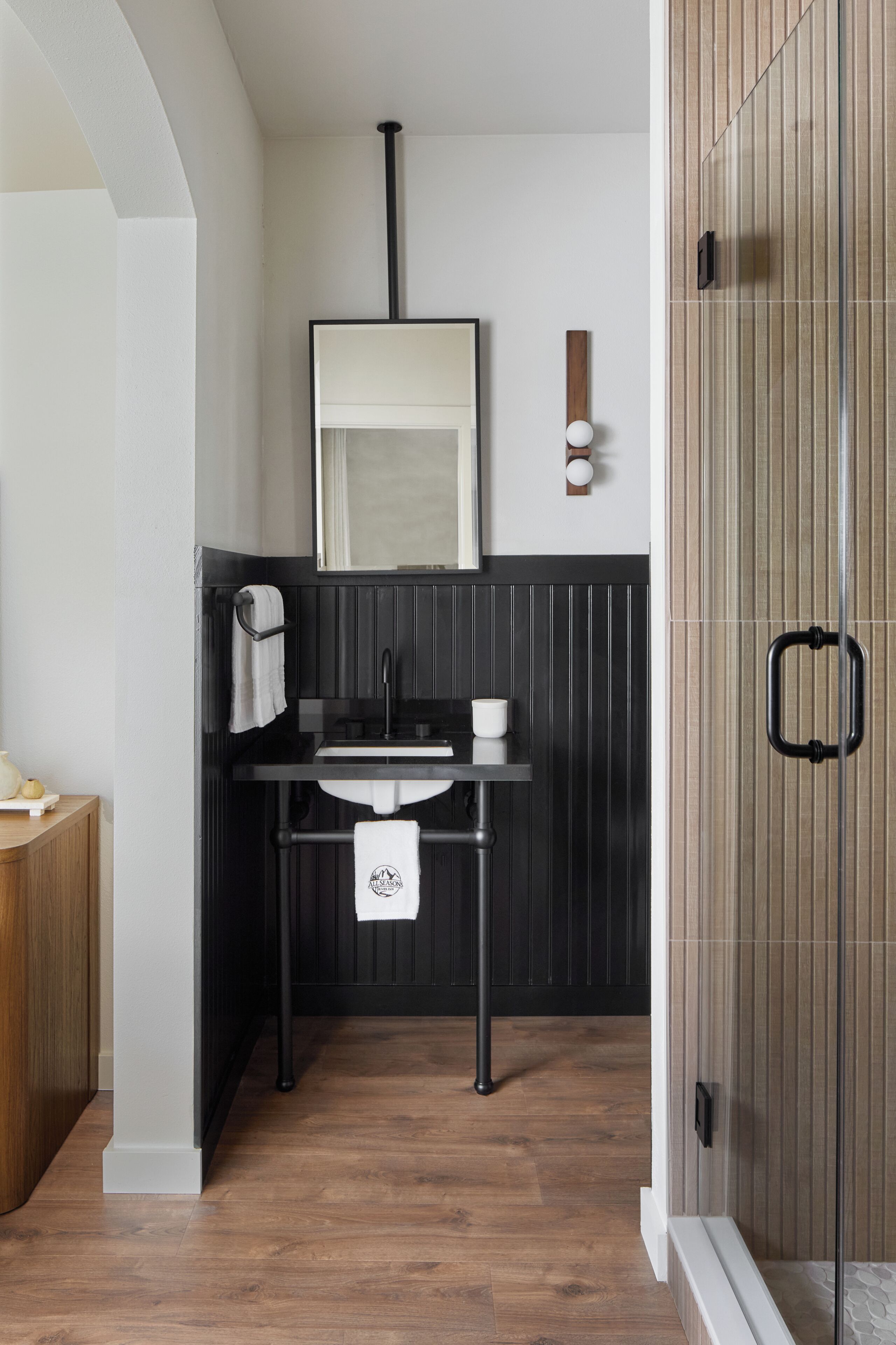 A bathroom with a black vanity, white sink, and a mirror.