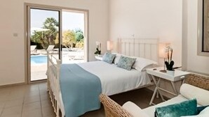 Une chambre à coucher avec un lit, une table de chevet, une lampe et une vue sur une piscine, visible à travers une porte coulissante.