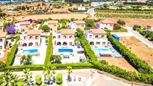 Une station balnéaire dotée de plusieurs villas, d’une piscine et offrant une vue sur la mer.