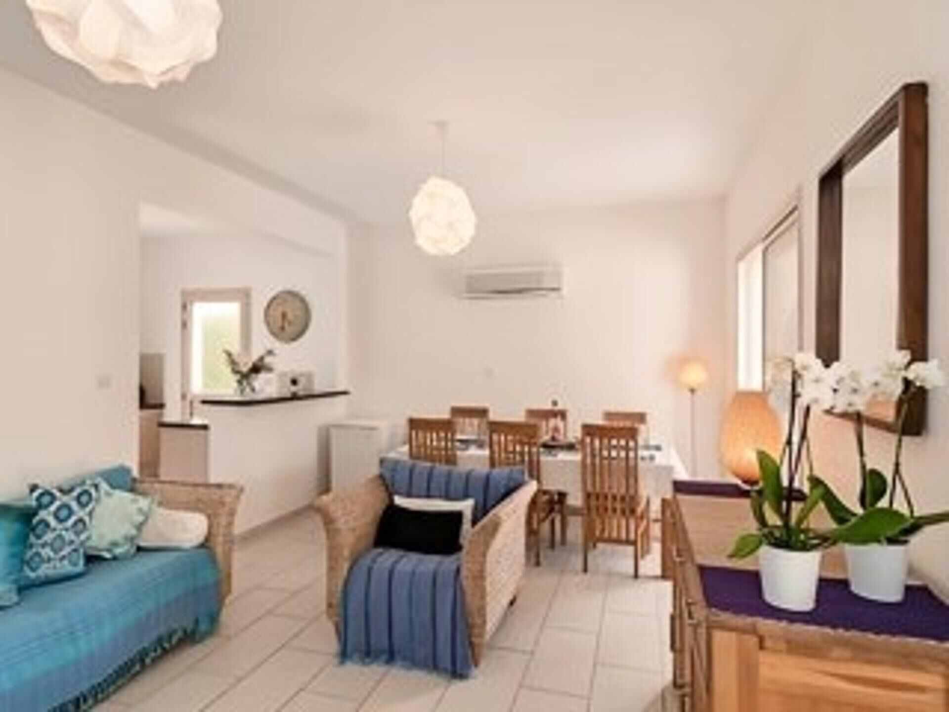Ein modernes Wohnzimmer mit einer Couch, einem Esstisch, Stühlen und einem großen Spiegel.