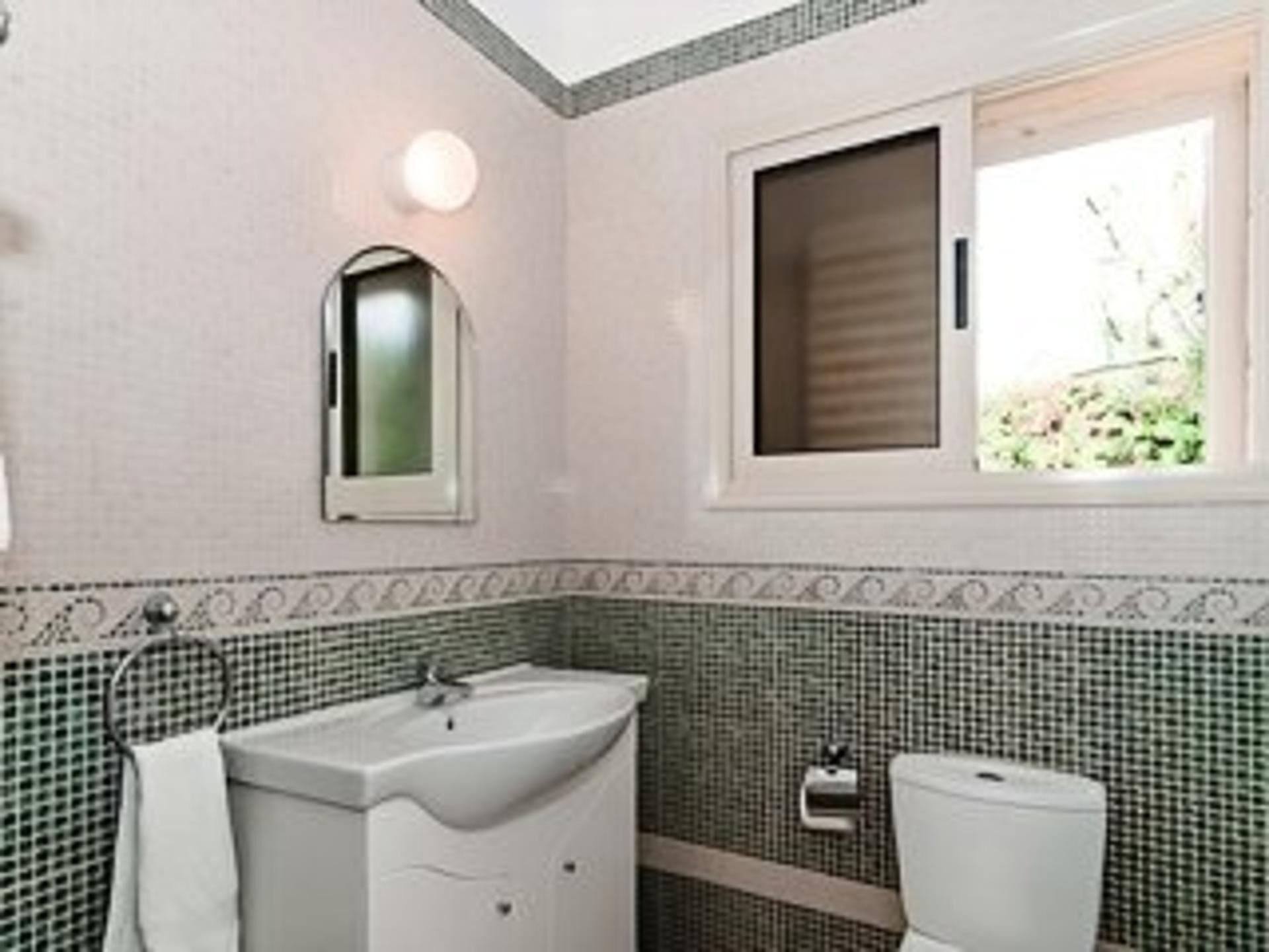 A bathroom with a sink, toilet, and a window.