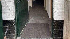 Uma entrada com porta verde e paredes de tijolos brancos.