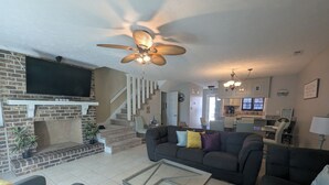 A living room with a fireplace, a sofa, a coffee table, and a ceiling fan. - Rusty Turtle Beach House (Myrtle Beach)
