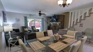 A dining area with a glass table, chairs, and a ceiling fan. - Rusty Turtle Beach House (Myrtle Beach)