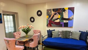 Et værelse med et spisebord, pink stole, en sofa og et billede på væggen.
