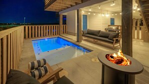 An outdoor pool area with a hot tub, a fire pit, and a seating area with a sofa and chairs.