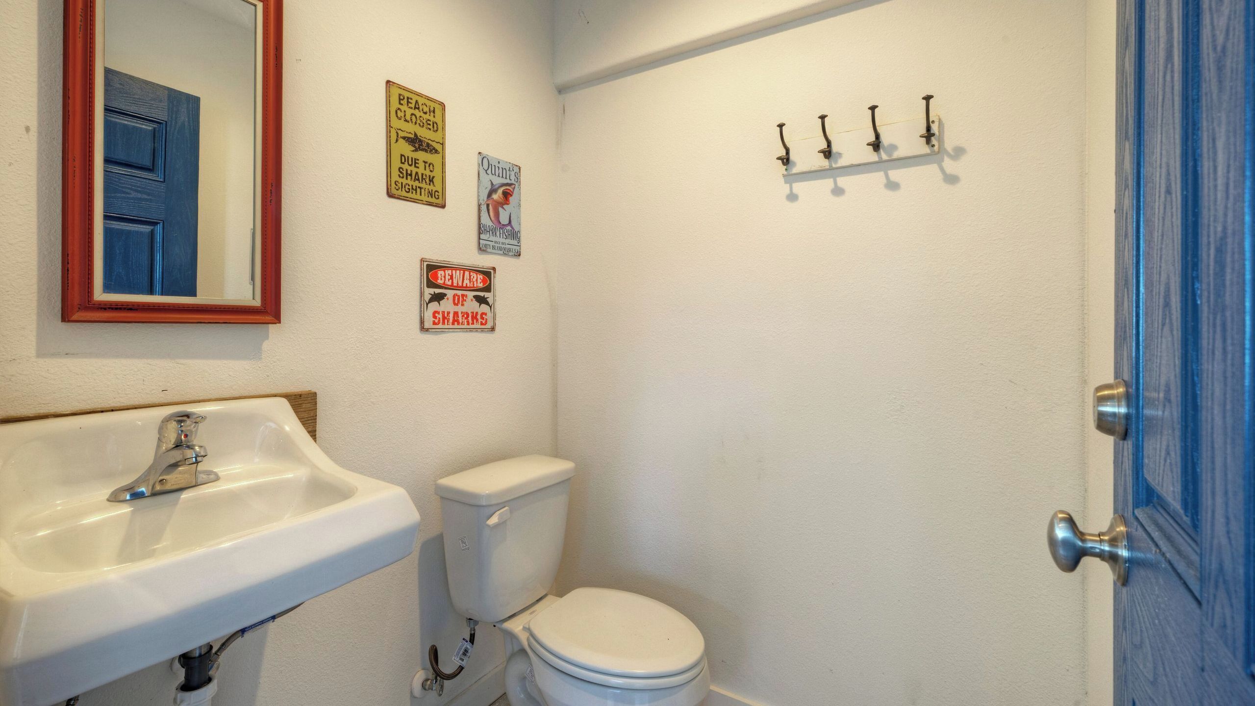 Uma casa de banho com lavatório, sanita e porta com estrutura azul.