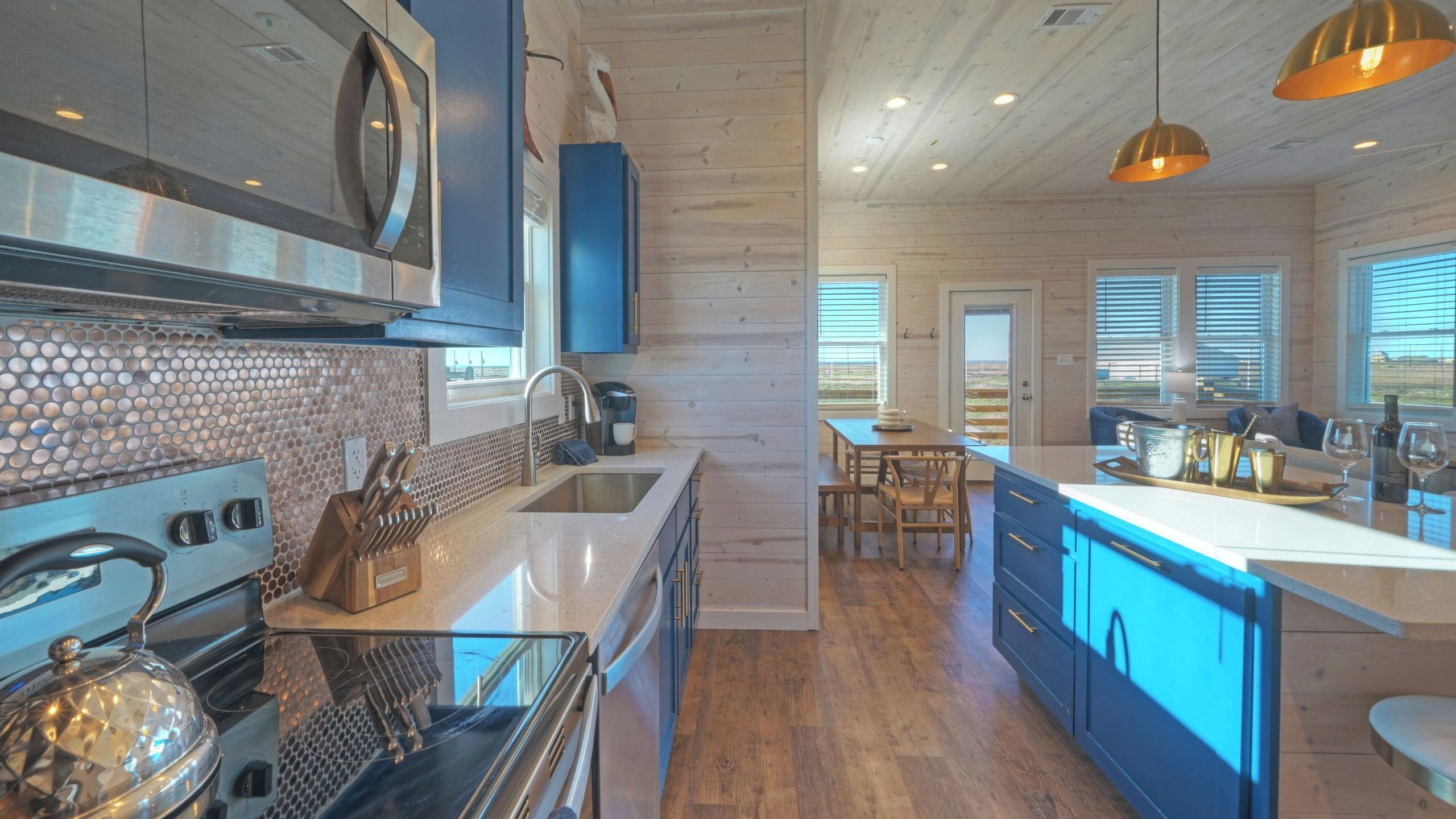 A modern kitchen with a large island, stainless steel appliances, and a wooden floor.