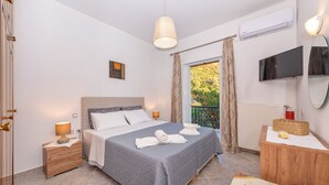 A bedroom with a bed, bedside tables, a TV, and a window with curtains.