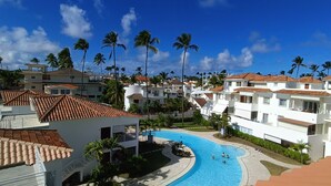A resort with multiple buildings, a swimming pool, and palm trees.