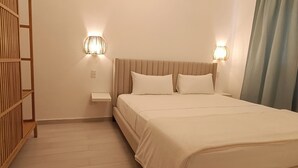 A bedroom with a bed, two wall-mounted lights, a nightstand, and a wooden shelf unit.
