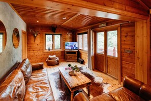 A wooden cabin interior with a leather sofa, a wooden table, and a television. - Floral Lodge 4 Great Ayton Yorkshire - sleeps 4 guests  in 2 bedrooms (Great Ayton)