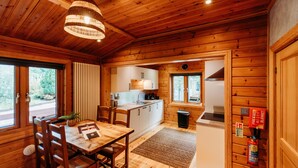 Ein Holzblockhaus-Innenraum mit Essbereich, Küche und einem sichtbaren Feuerlöscher.