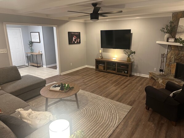 A living room with a sofa, a coffee table, a fireplace, a TV, and a ceiling fan. - Masters 2026 Rental! 3 Bed 2 Bath! (Martinez)