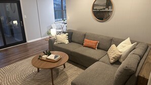 A modern living room with a grey sectional sofa, a round coffee table, and a patterned rug. - Masters 2026 Rental! 3 Bed 2 Bath! (Martinez)