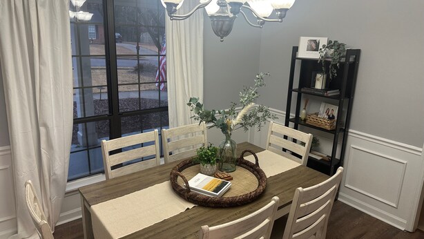 A dining area with a wooden table, white chairs, a woven placemat, and a vase with greenery. - Masters 2026 Rental! 3 Bed 2 Bath! (Martinez)
