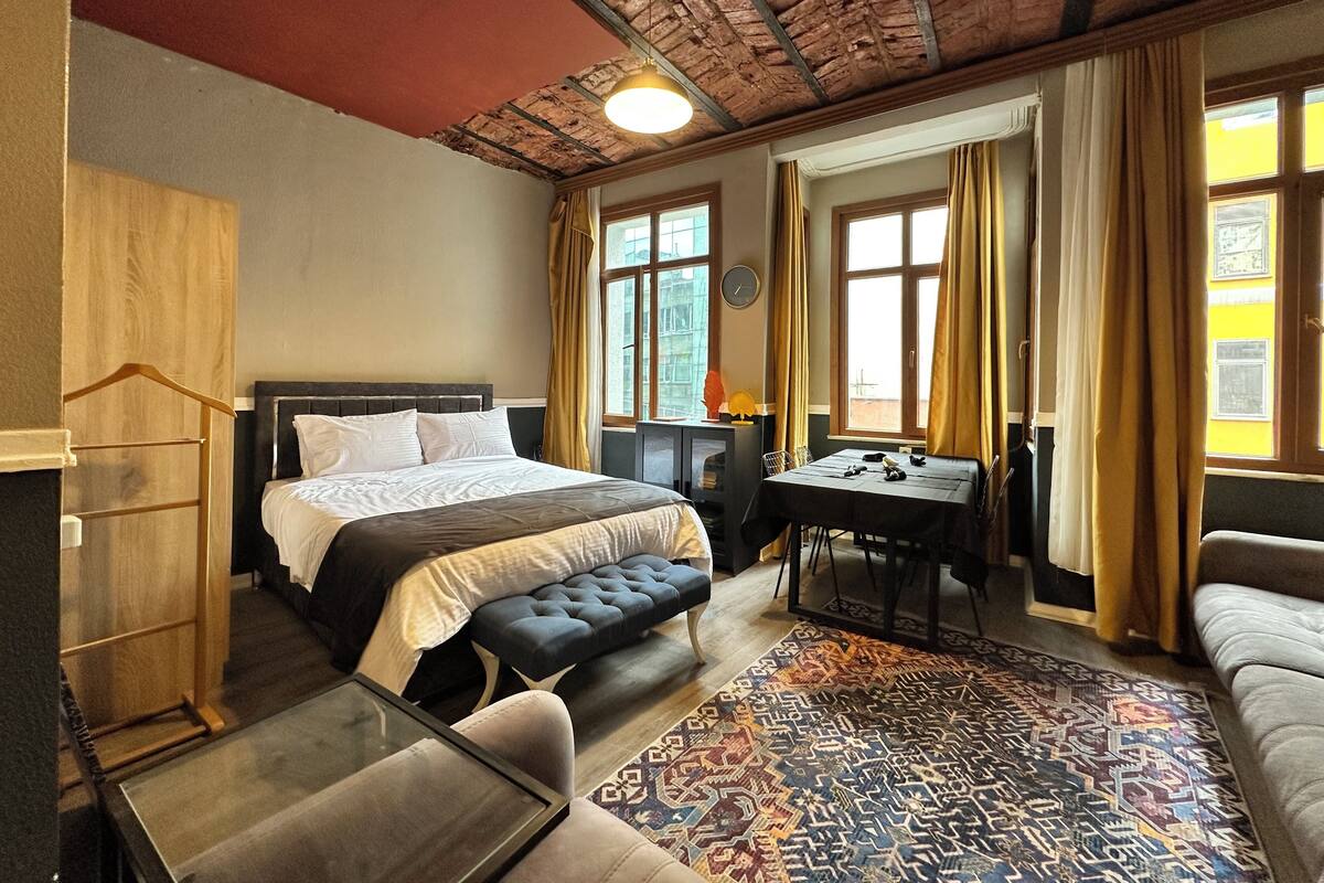 Ein Hotelzimmer mit einem großen Bett, einem Schreibtisch, einer Couch und einem gemusterten Teppich.