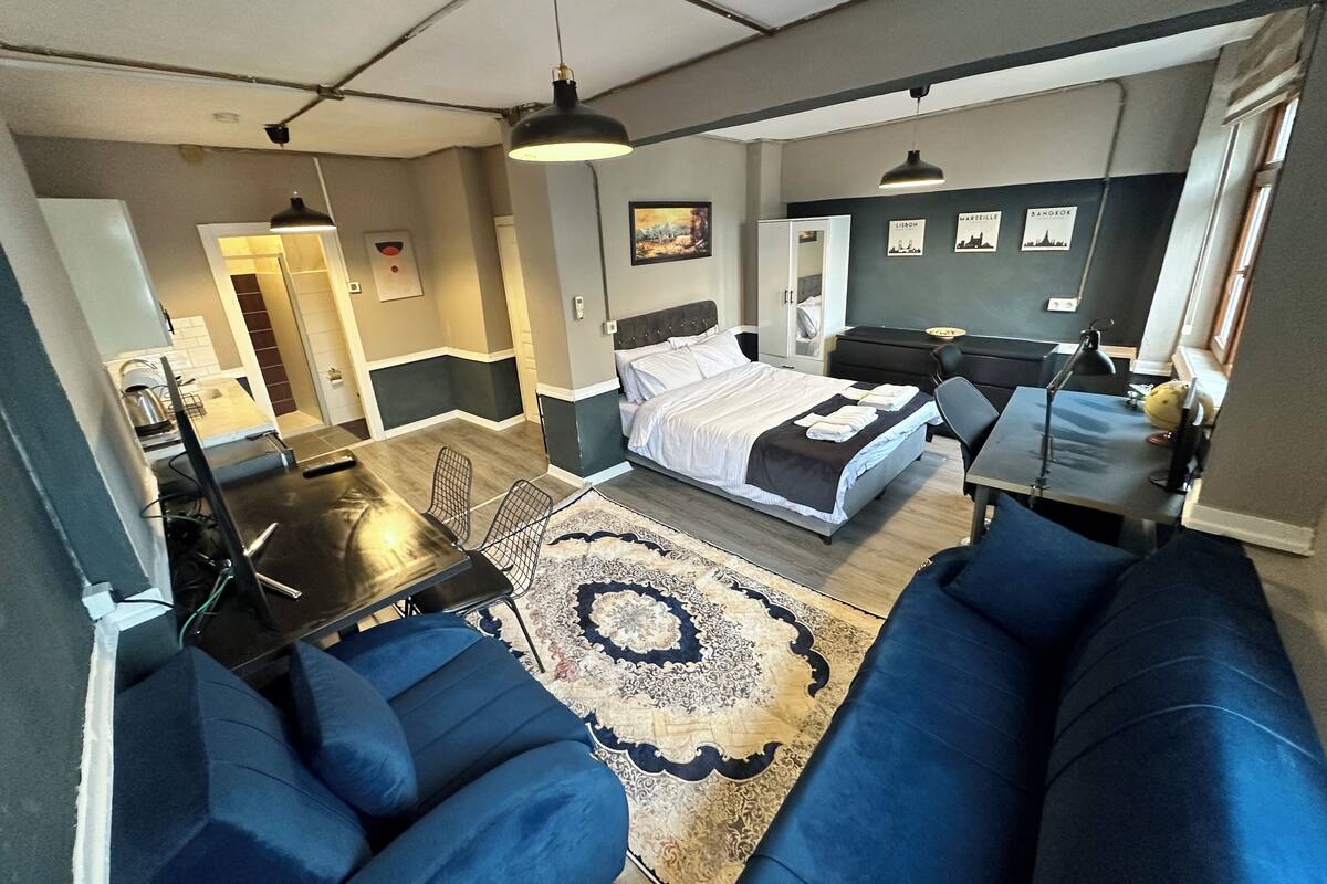 Ein modernes Hotelzimmer mit einem großen Bett, einer Couch, einem Schreibtisch und einem Essbereich.