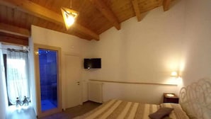 Une chambre avec un grand lit, un téléviseur fixé au mur et un plafond en bois.