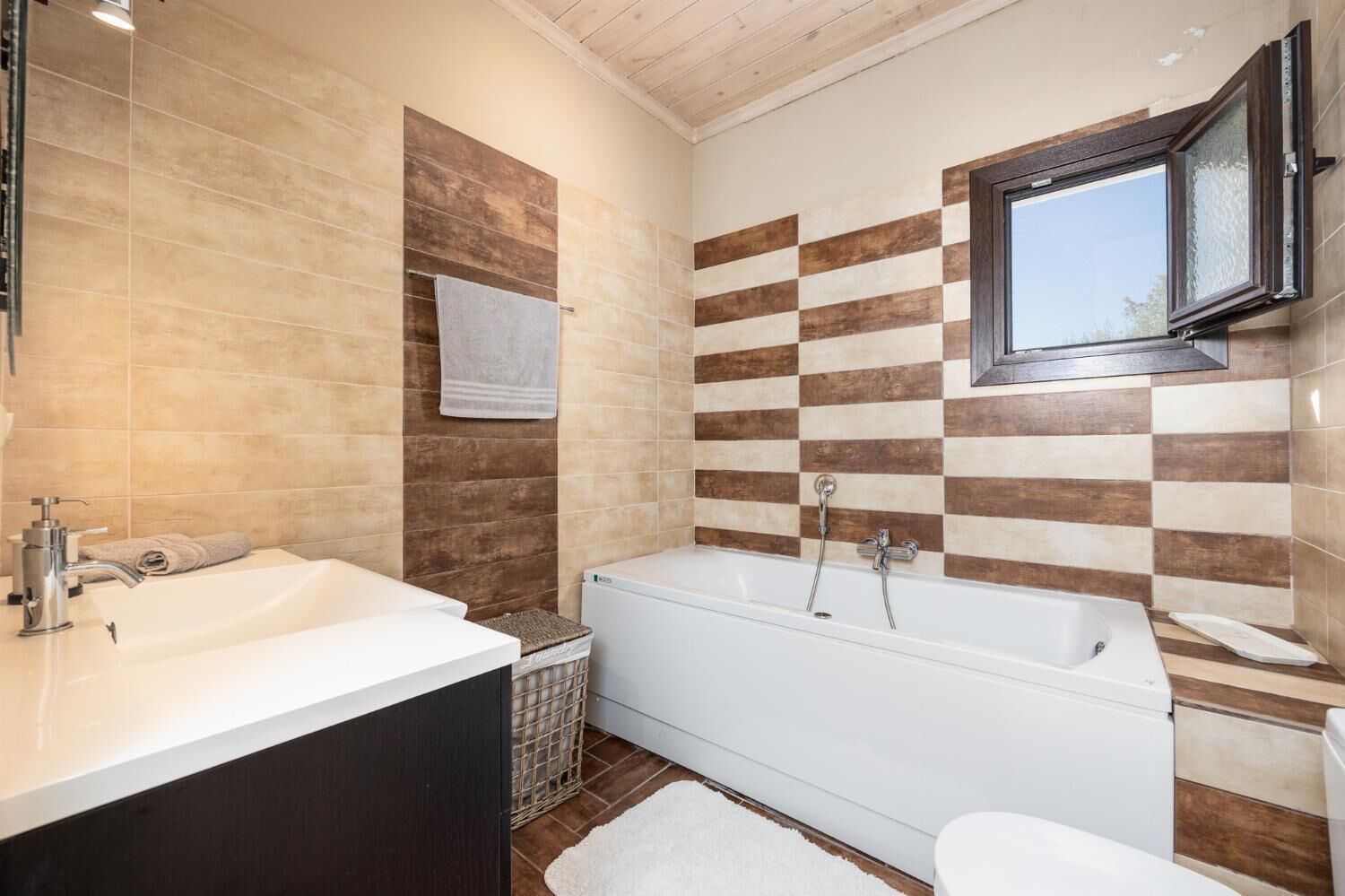 A bathroom with a bathtub, a sink, and a window.