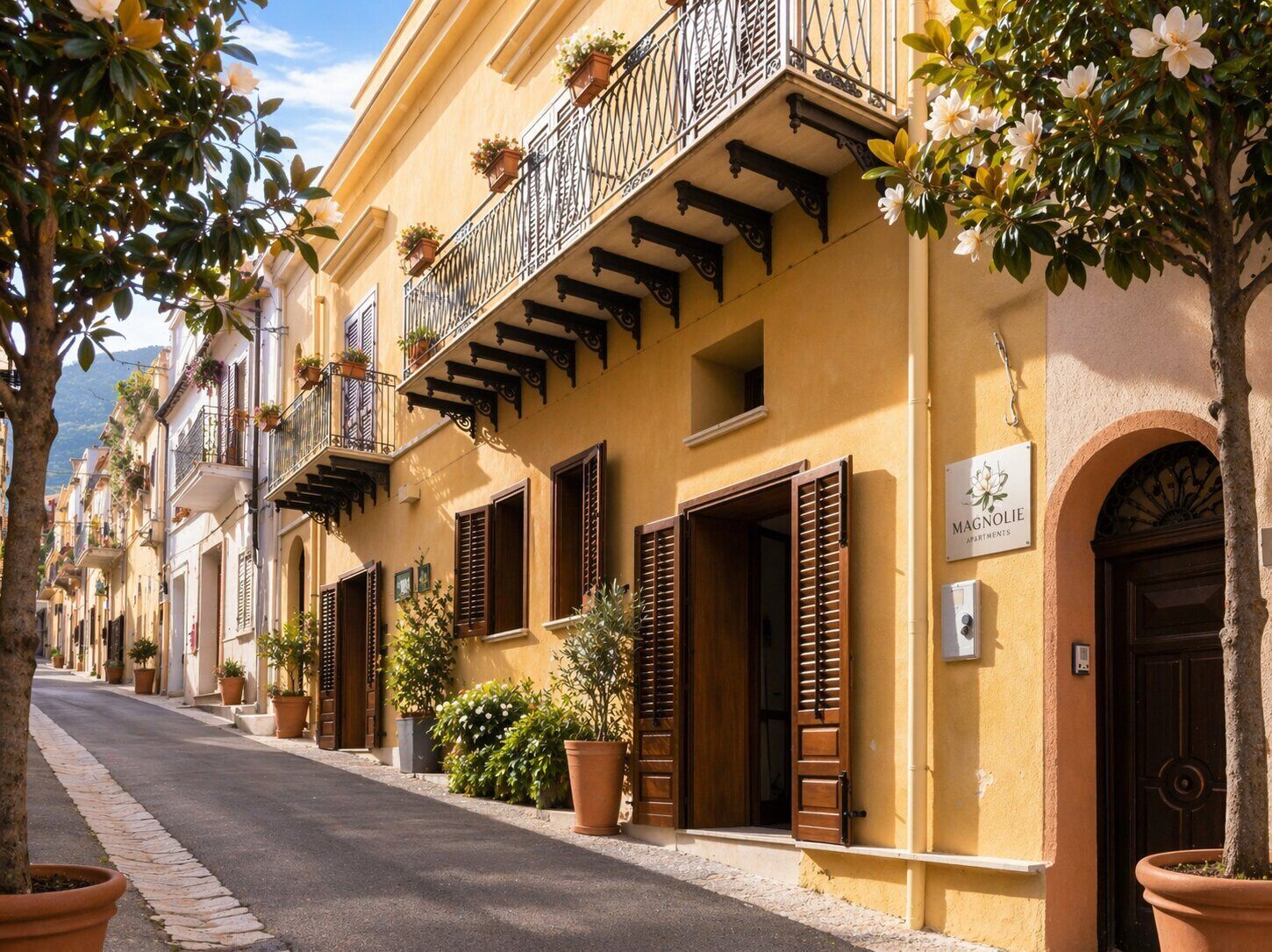 Rua com edifícios amarelos, persianas de madeira e varandas com plantas em vasos.