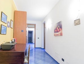 Ein Hotelkorridor mit einem Holztisch, Stühlen und einem Gemälde an der Wand.