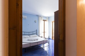 A bedroom with a bed, a window with curtains, and a door.