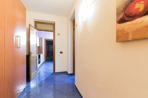 Ein Flur mit blauen Fliesen, Holztüren und einem Gemälde an der Wand.