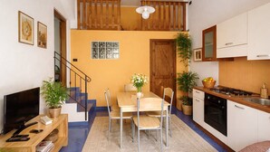 Un espace de vie compact comprenant un coin repas, une cuisine et un escalier menant à un niveau supérieur.