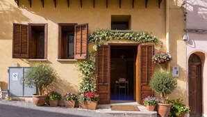 Un bâtiment avec une porte en bois, une petite fenêtre et un balcon orné de plantes en pot.