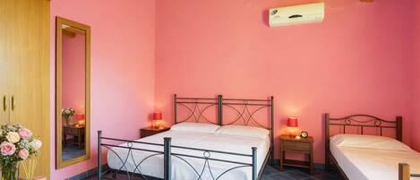 Een slaapkamer met een bed, nachtkastjes, een spiegel, een kledingkast en een plafondventilator.