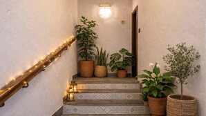 Una escalera adornada con luces decorativas, plantas en macetas y una lámpara fijada a la pared.