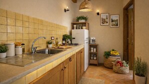 A kitchen with a tiled backsplash, stainless steel sink, wooden cabinets, a white refrigerator, and a hanging light fixture. - Visitsicilia 6 Le Magnole 6 (Castellammare del Golfo)