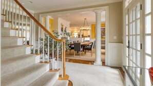 Un escalier avec une rampe en bois menant à un espace repas comprenant une table et des chaises.