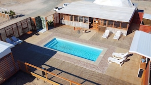 Area piscina sul tetto con poltrona prendisole, piscina e zona relax coperta.