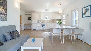 A modern living room with a gray sofa, a white coffee table, and a dining area with white chairs and a table. - Villa Milna Bay, heated pool, Milna, Brač Island (Milna)