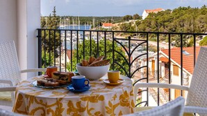 A balcony with a table set for breakfast, overlooking a marina and coastal town. - Villa Milna Bay, heated pool, Milna, Brač Island (Milna)