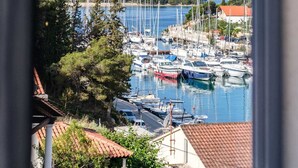 A marina with multiple boats docked, surrounded by greenery and buildings with red-tiled roofs. - Villa Milna Bay, heated pool, Milna, Brač Island (Milna)