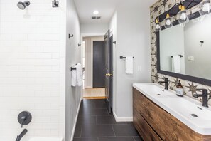 Een moderne badkamer met een douche, een wastafel met spiegel en een handdoekrek.