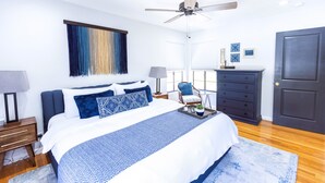 A modern bedroom with a large bed, a ceiling fan, a dresser, and a window with blinds. - Second Floor Serenity in a Great Location! (San Antonio)