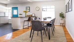 A modern kitchen with a blue door, a dining area with a wooden table and chairs, and a large window providing natural light. - Second Floor Serenity in a Great Location! (San Antonio)