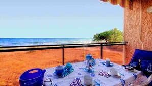 Ein Esstisch, gedeckt für das Frühstück, mit Blick auf Strand und Meer.