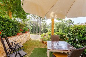 An outdoor patio with a table and chairs, surrounded by greenery and a stone wall. - Romantic Tuscan Cottage with Pool and Garden (Toscana)