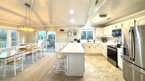 A modern kitchen with white cabinetry, stainless steel appliances, and a large island. - 4x4 Carova, WaterFront, Dock, Wild Horses, Hot Tub (Corolla)